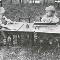 Lavori all'aria aperta Two year olds in the garden of the Children's House Berlin-Lankwitz, 1919-22. The little girl on the left is practising buttoning on one of the dressing frames; the child on the right is busy with the cylinder insets of different diameters. This photograph from 1920 was also published in 1927 in the Berliner Illustrirte Zeitung - T. Müller, R. Schneider, <em>Lehrmaterialien 1913-1935. Möbel und Architektur. Techning Meterials 1913-1935. Furniture and Architecture</em>, München, Prestel Verlag, 2002, p.90$$$447