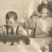 Materiale sensoriale, Berlino Children abosorbed in sensory exercises with cylinderinsets ans sound boxes in a Berlin Children's House. Postcard published by the DMG (German Montessori Society), around 1927 - T. Müller, R. Schneider, <em>Lehrmaterialien 1913-1935. Möbel und Architektur. Techning Meterials 1913-1935. Furniture and Architecture</em>, München, Prestel Verlag, 2002, p.21.$$$367